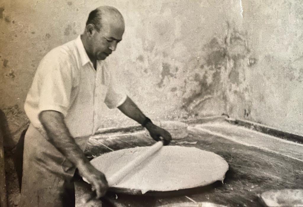 Black-and-white photograph of Abdallah Zalatimo I rolling paper-thin dough by hand on a marble slab